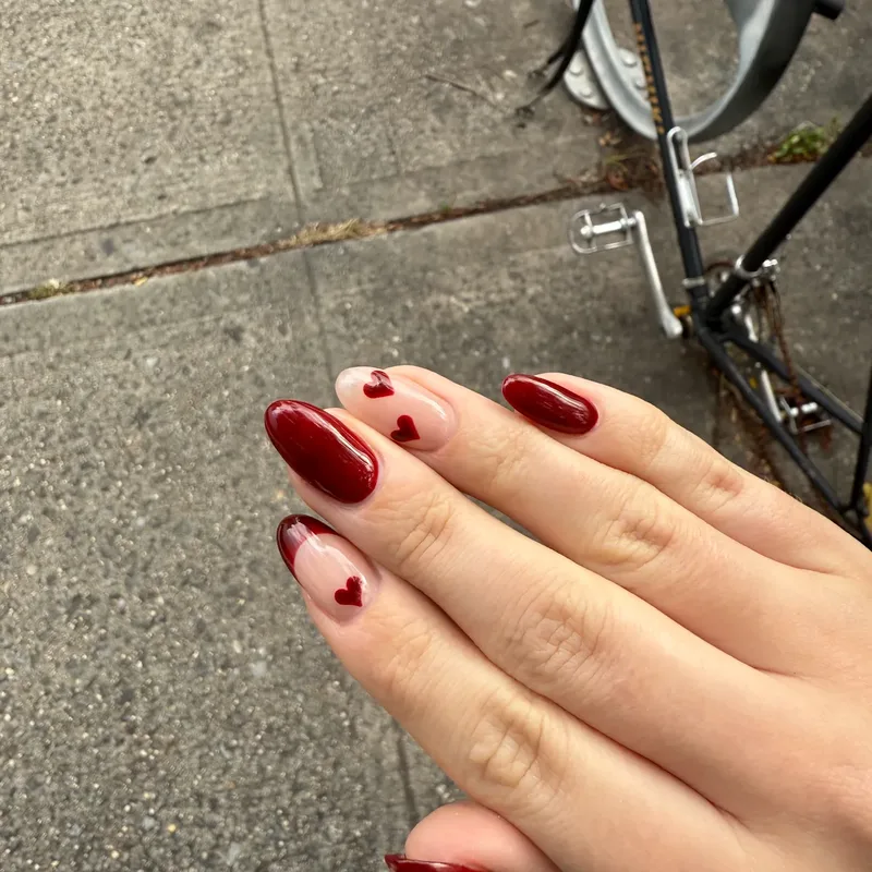 Cherry red almond nails with heart accents by Tina Green Nail